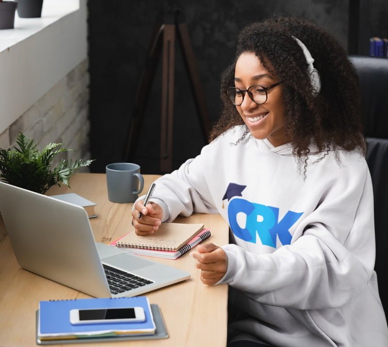 A healthcare professional studying on a laptop with CRK Courses' logo, showcasing the benefits of free CPD-accredited courses, diverse topics, and capacity-building training